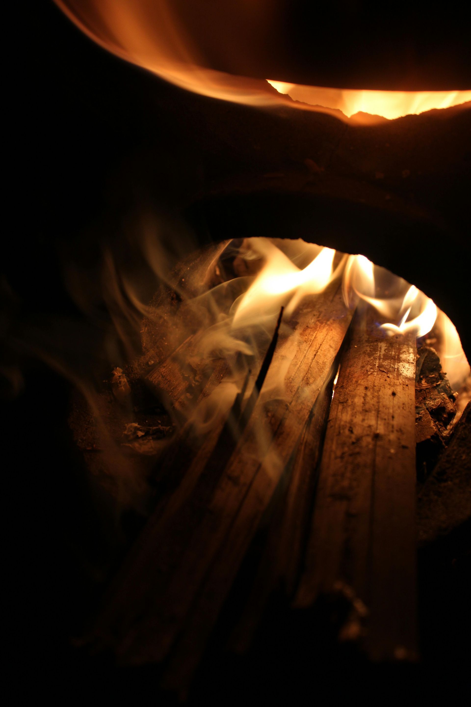 Fire burning inside a dark enclosure, with flames and smoke visible.