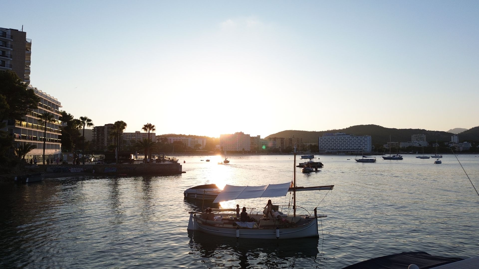 Llaut navegando por el mar con la puesta de sol a lo lejos, ideal para un tour en barco en Mallorca.