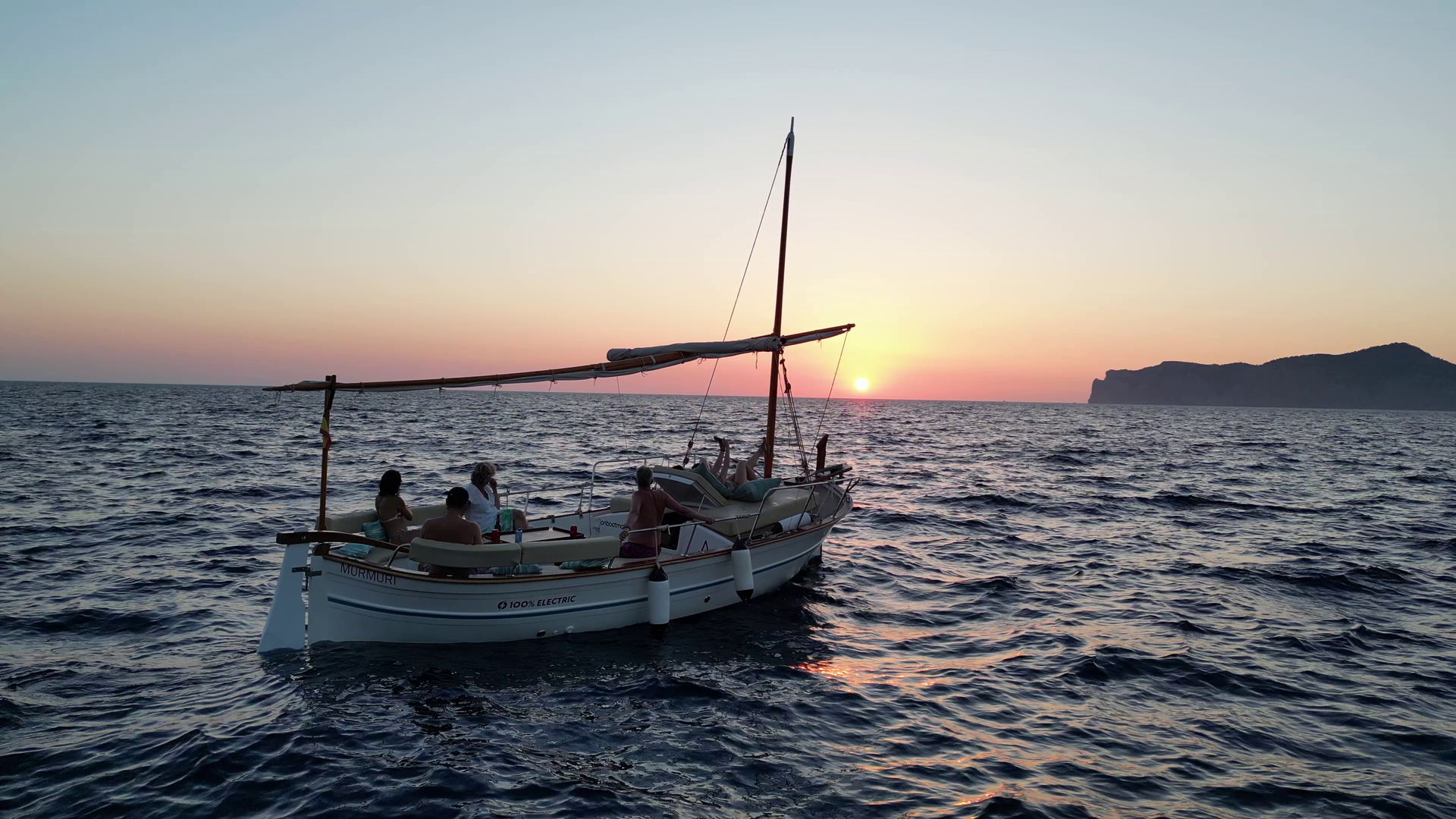 Llaut navegando por el mar con la puesta de sol a lo lejos, ideal para un tour en barco en Mallorca.