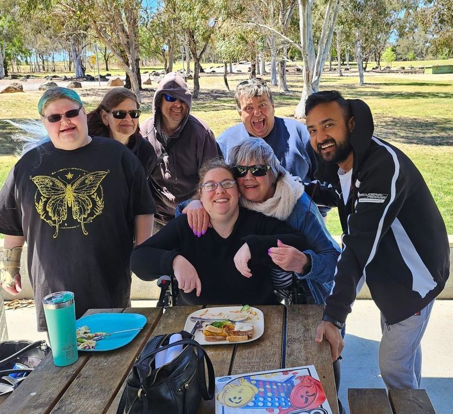 A group of people posing for a picture at a picnic table