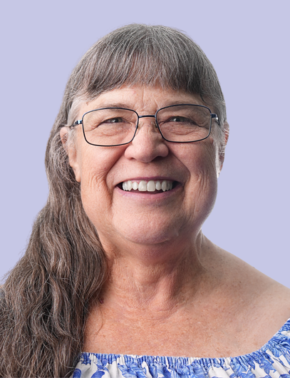 A woman with red hair and glasses is smiling for the camera.