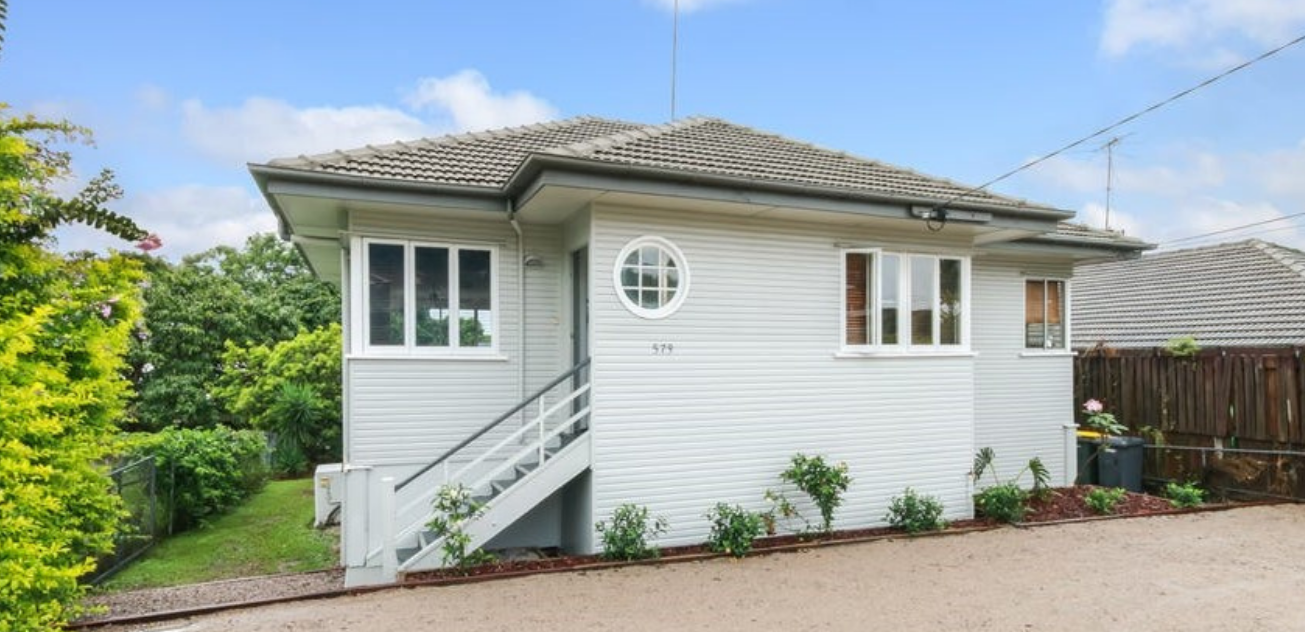 A small white house with stairs leading up to it is for sale.