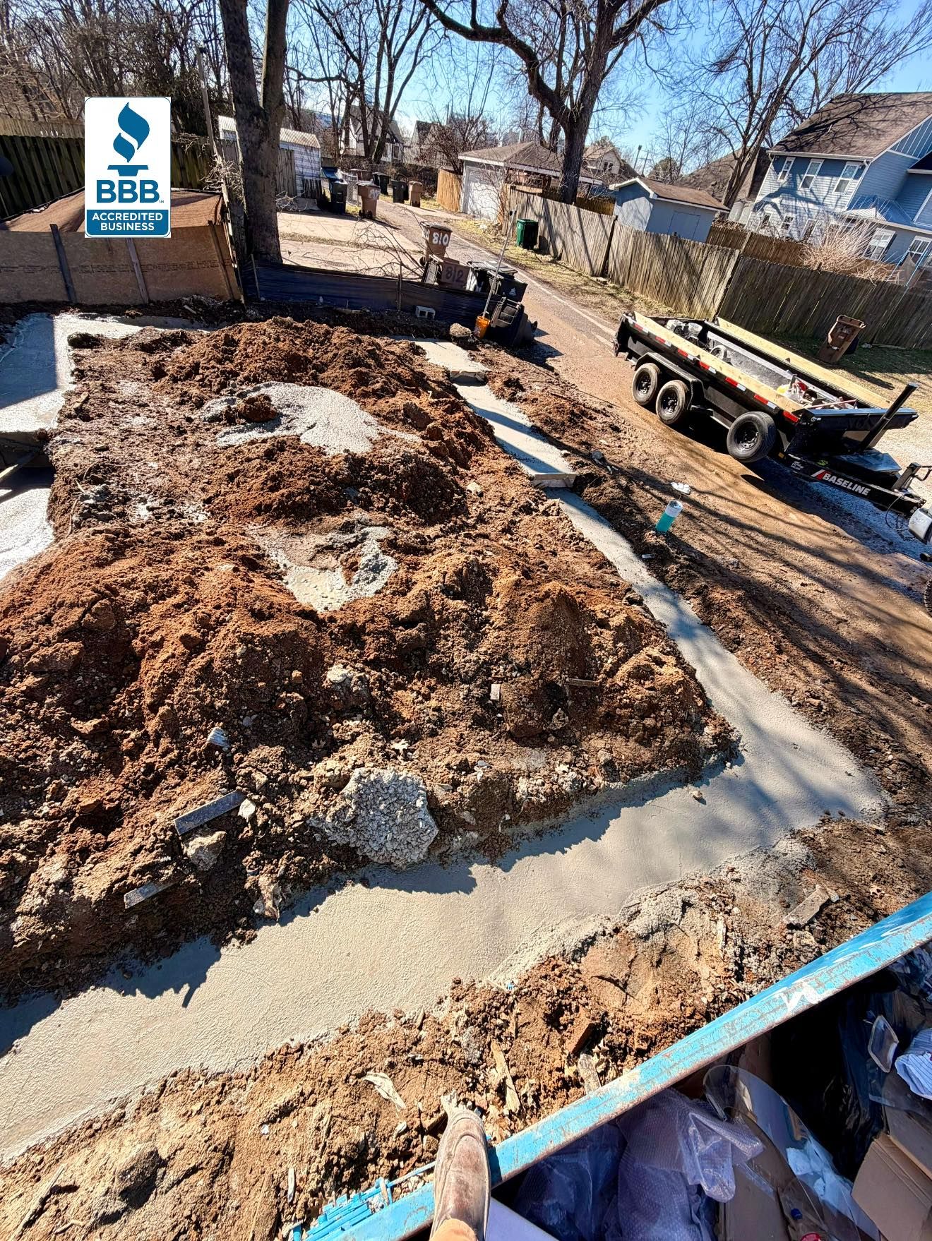 Construction site with excavated earth, concrete foundation, and a trailer on the side.