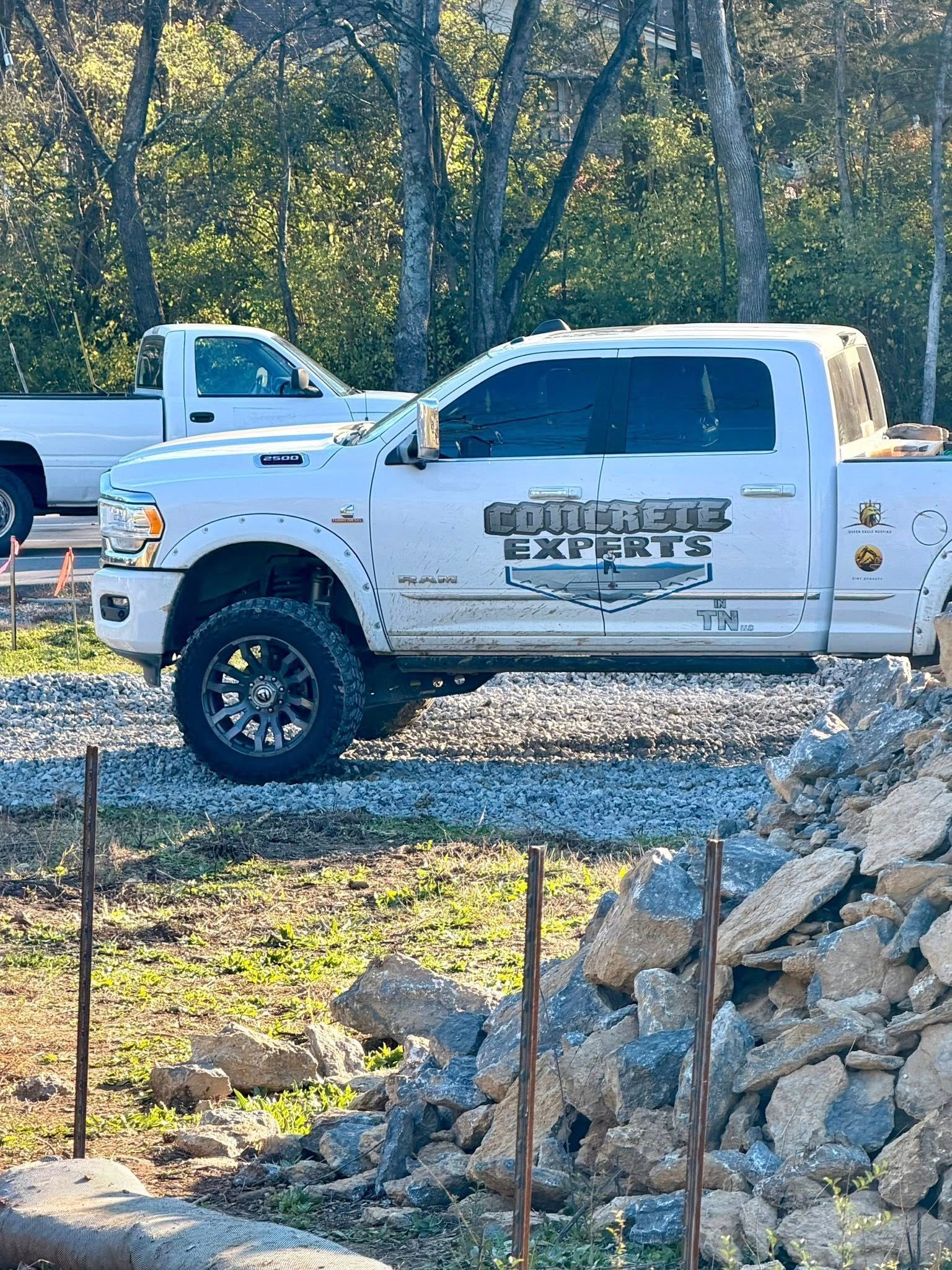White concrete truck with company logo parked on gravel. Another truck in background.