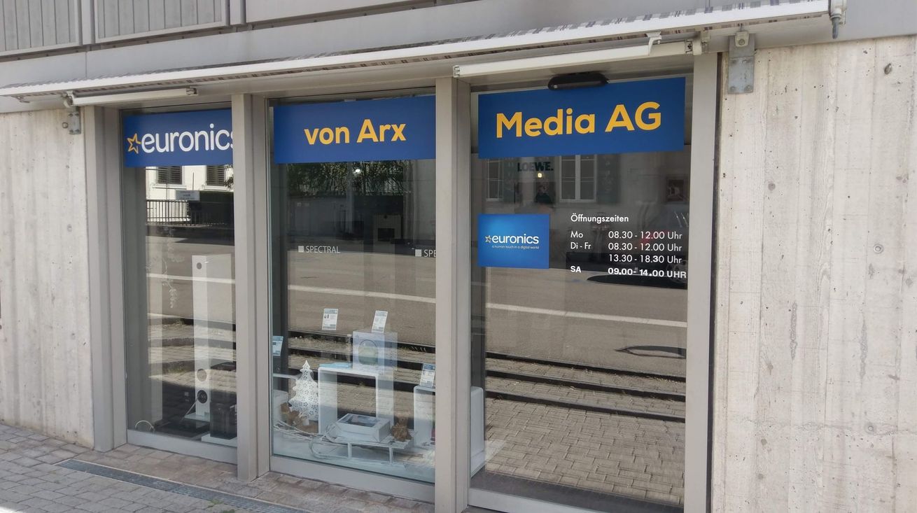 Euronics Zollinger-Geschäftsfront mit blauen Schildern und gläsernem Eingang an einem Kopfsteinpflasterweg