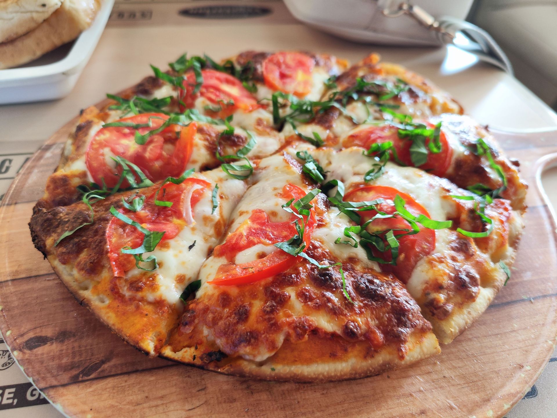 Close-up of a margherita pizza with melted cheese, tomatoes, and basil on a wooden board