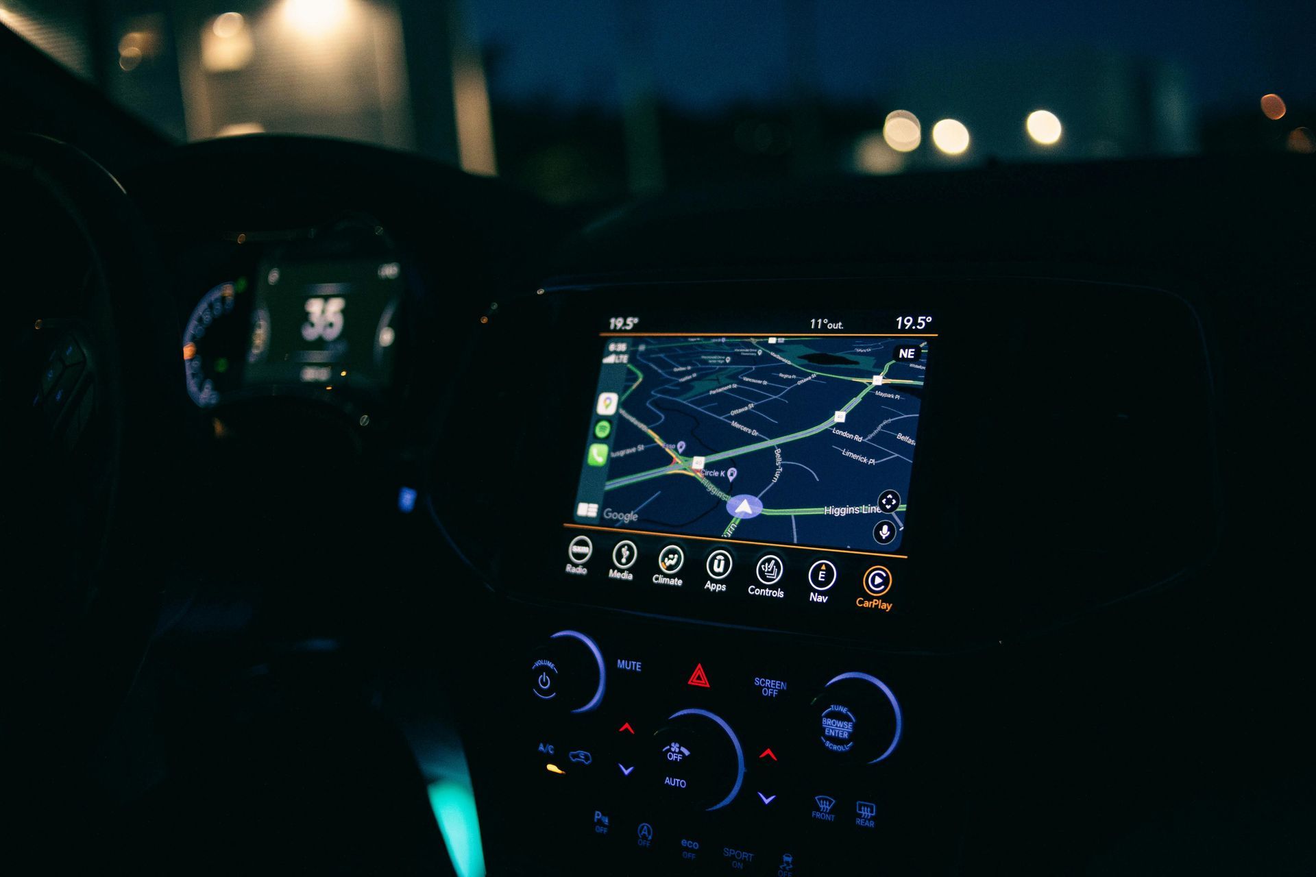 Car dashboard at night with illuminated GPS navigation screen and climate controls in a dark interior