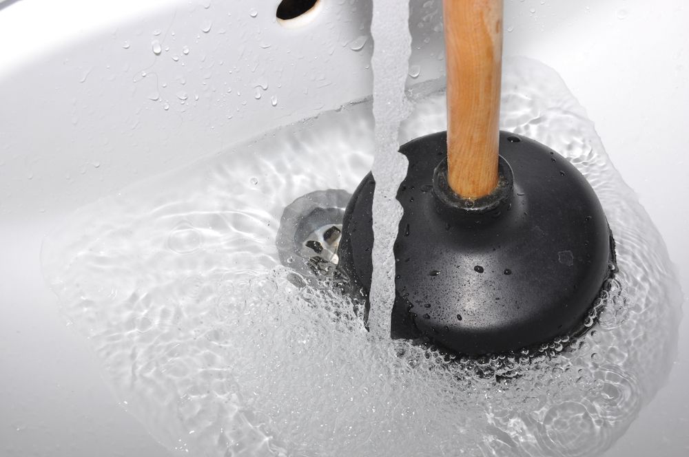 Plunger Clearing a Clogged White Sink Drain — One Flush Plumbing Service In Ormeau, QLD