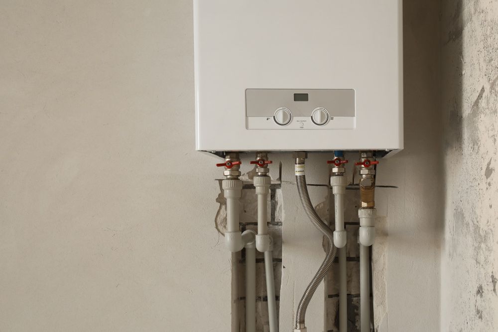 A White Boiler with Pipes Attached to It Is Hanging on A Wall — One Flush Plumbing Service In Oxenford, QLD