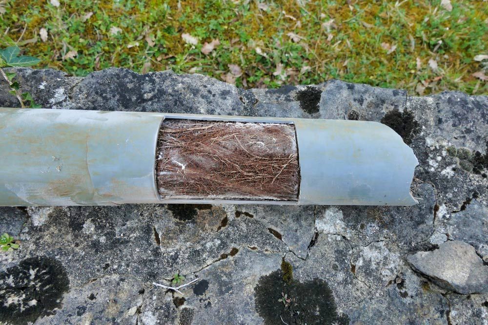 A Metal Pipe with A Hole in It Is Sitting on A Rock — One Flush Plumbing Service In Oxenford, QLD