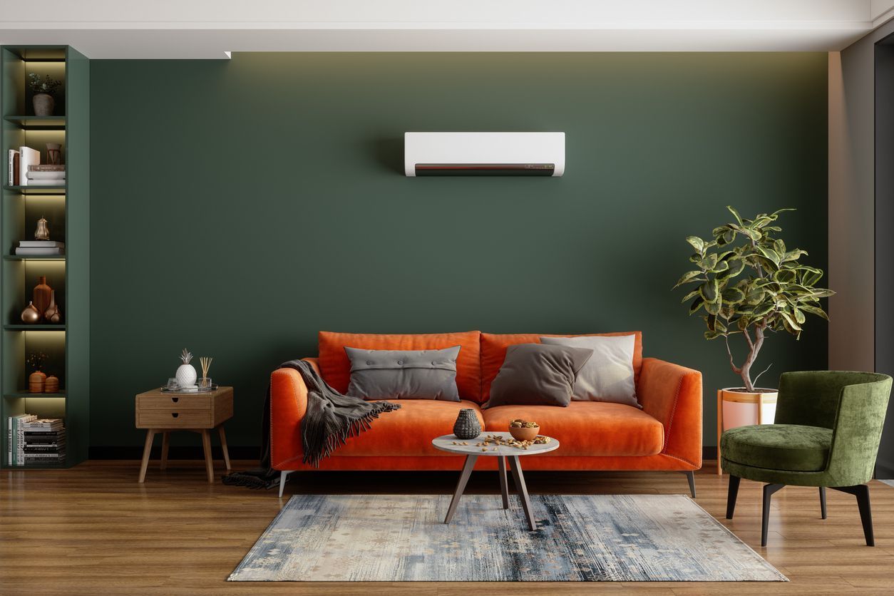 Orange sofa in a living room with green accent wall, wooden floor, and decorative items.