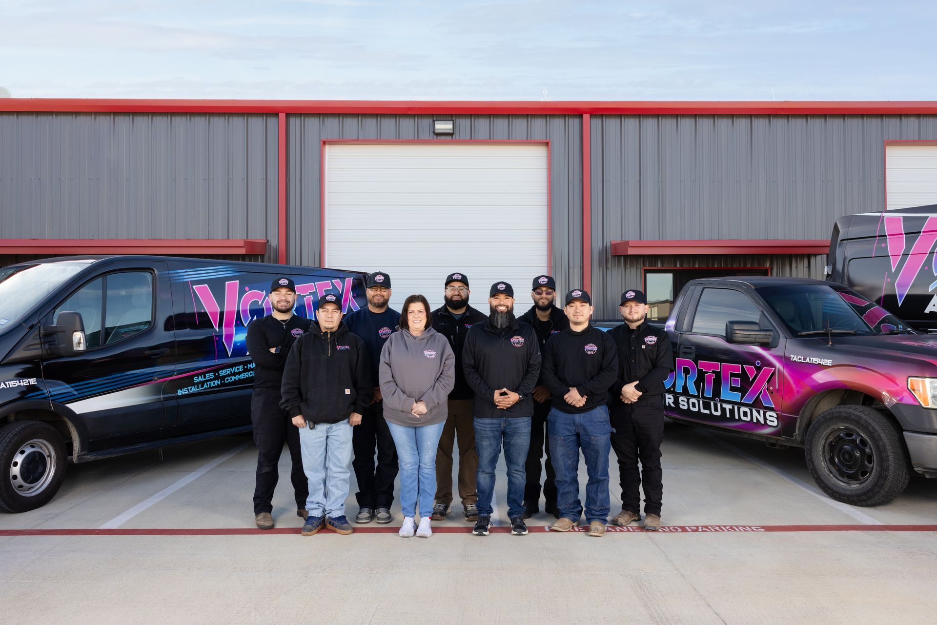 A truck with trailer is parked in a driveway. The truck and trailer are branded with 