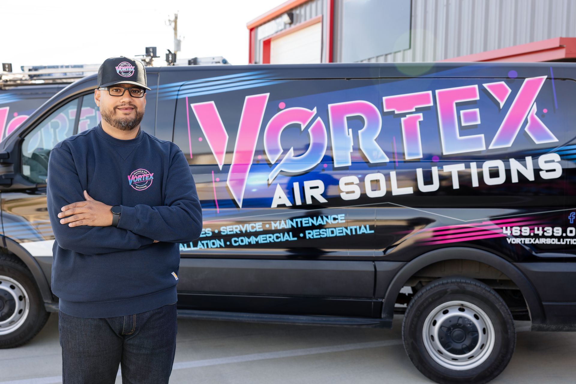 HVAC technician working on an AC unit outside a brick building.
