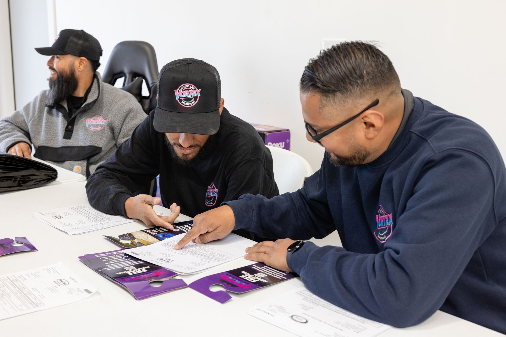 Couple relaxing on a couch, looking at a tablet and a phone in a living room, smiling.
