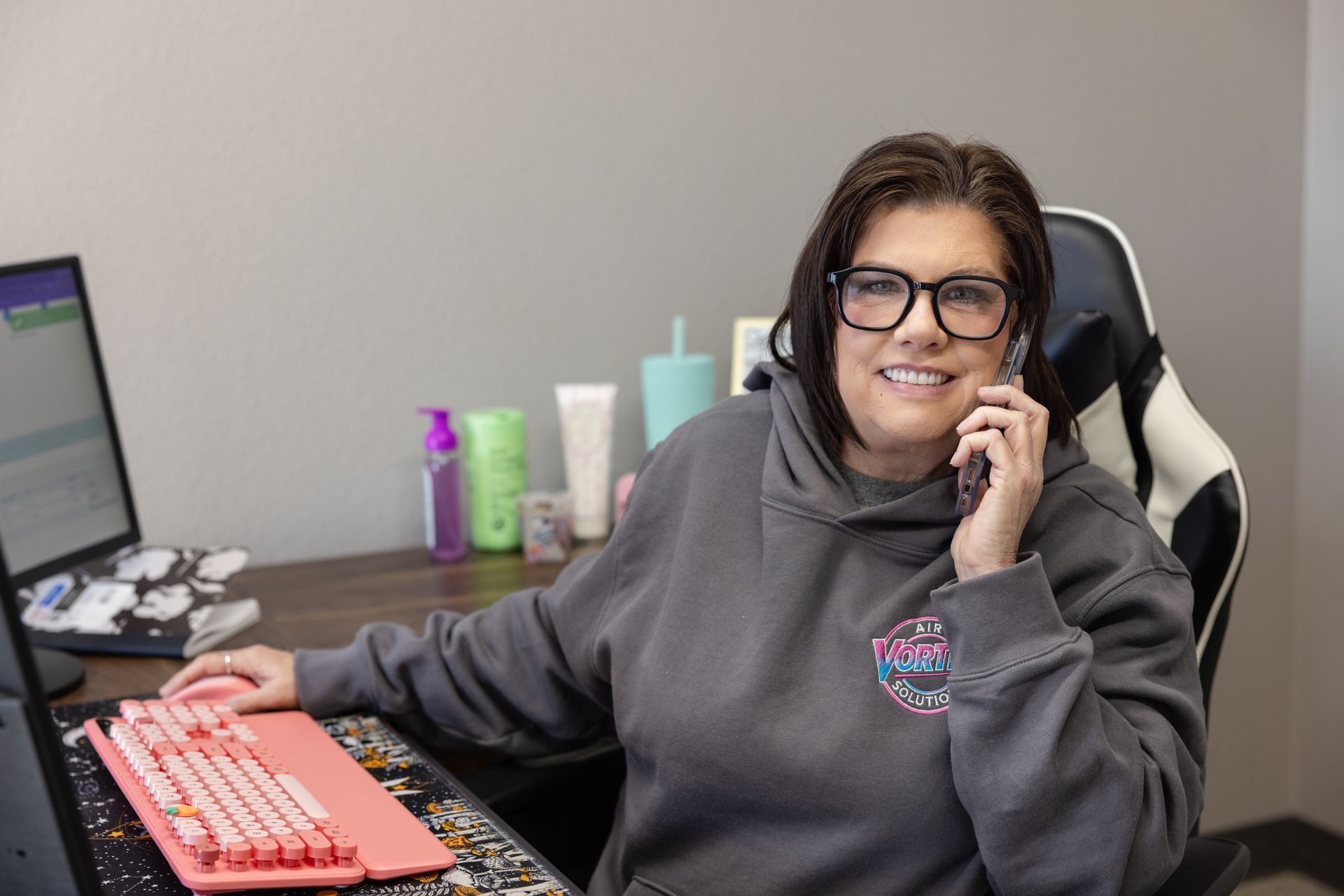 Woman adjusting thermostat on a white wall in a modern kitchen. Man in background.