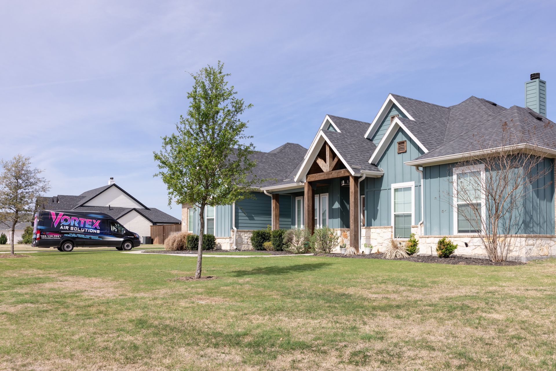 Person in blue overalls repairs an air conditioning unit outside, wearing gloves.