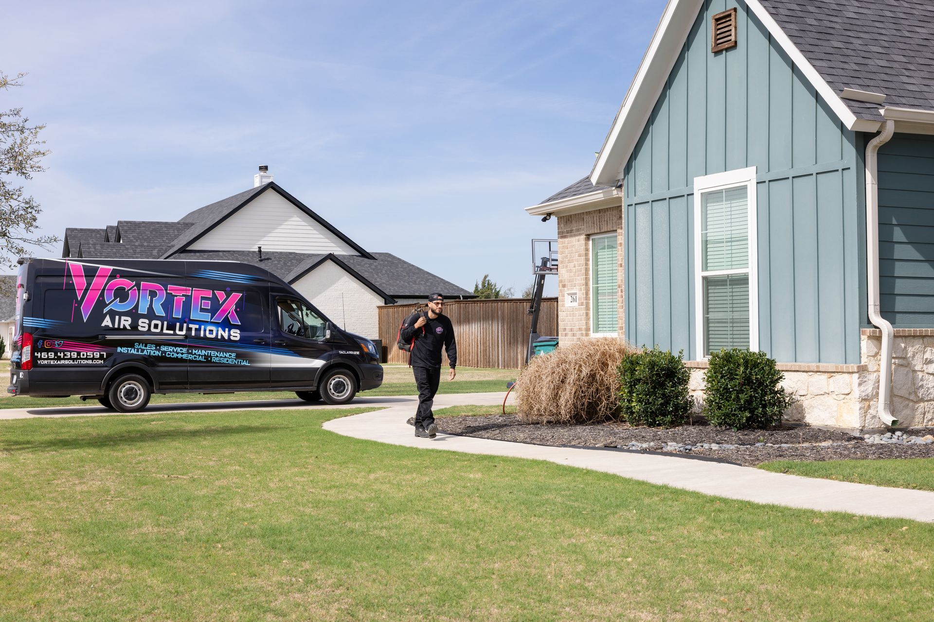 Red brick courthouse with clock tower and trees, sunny day.