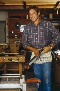 A man in a plaid shirt is standing in a workshop