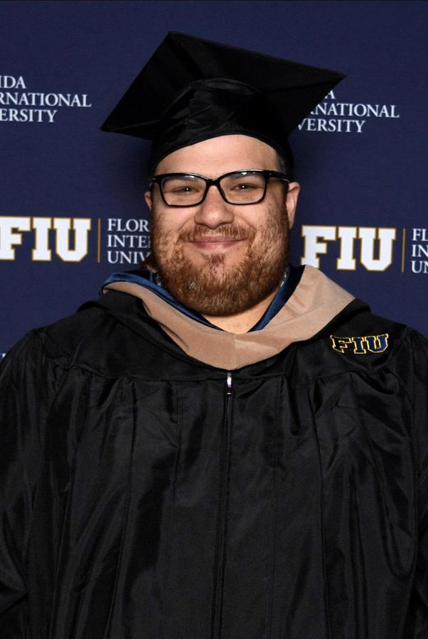 a man with a beard wearing a graduation cap and gown