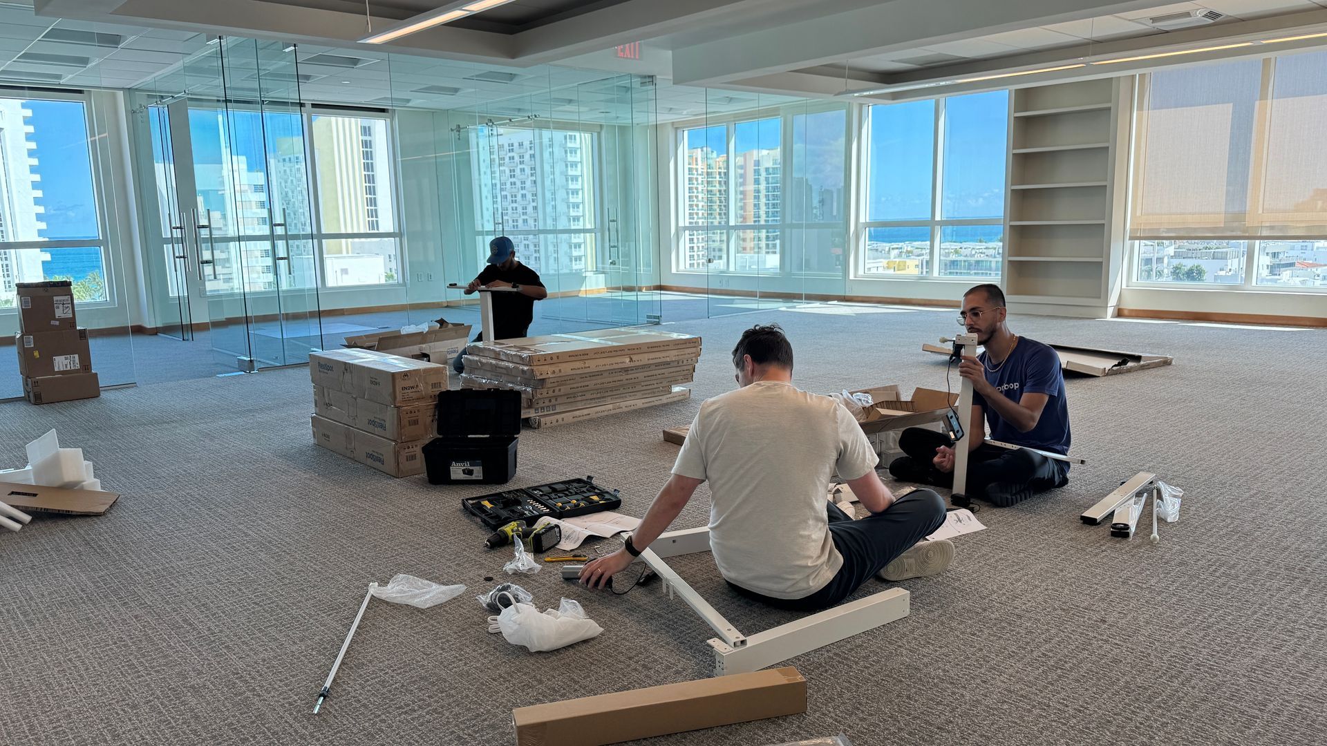 Two men are sitting on the floor in an empty room.