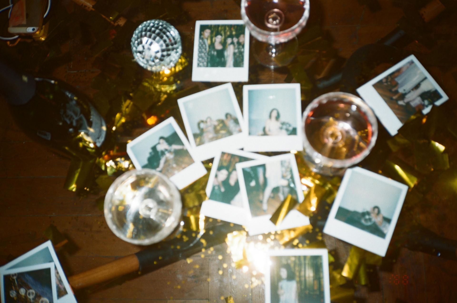 A table topped with polaroid pictures , champagne glasses , and disco balls.