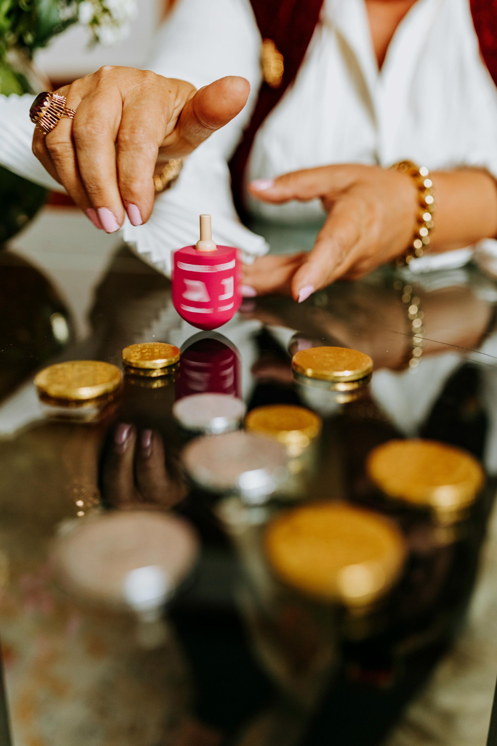 A woman is playing a game of dreidel with coins on a table.