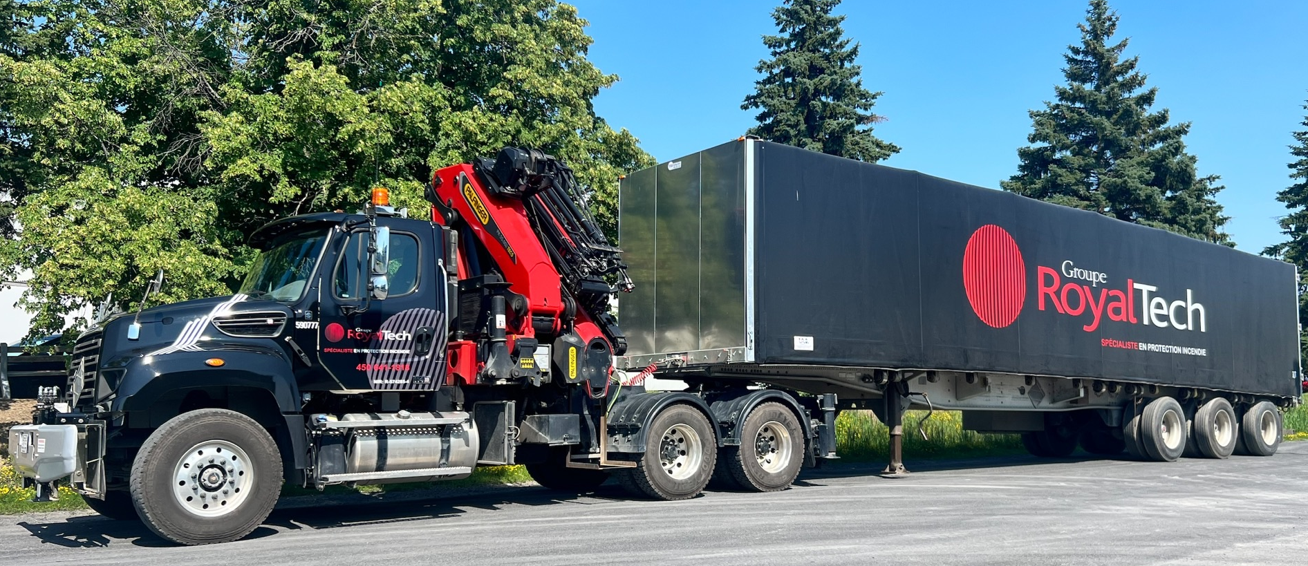 A truck with a crane attached to it is parked in a parking lot.