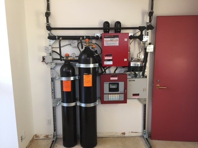 A red door is behind a fire alarm system