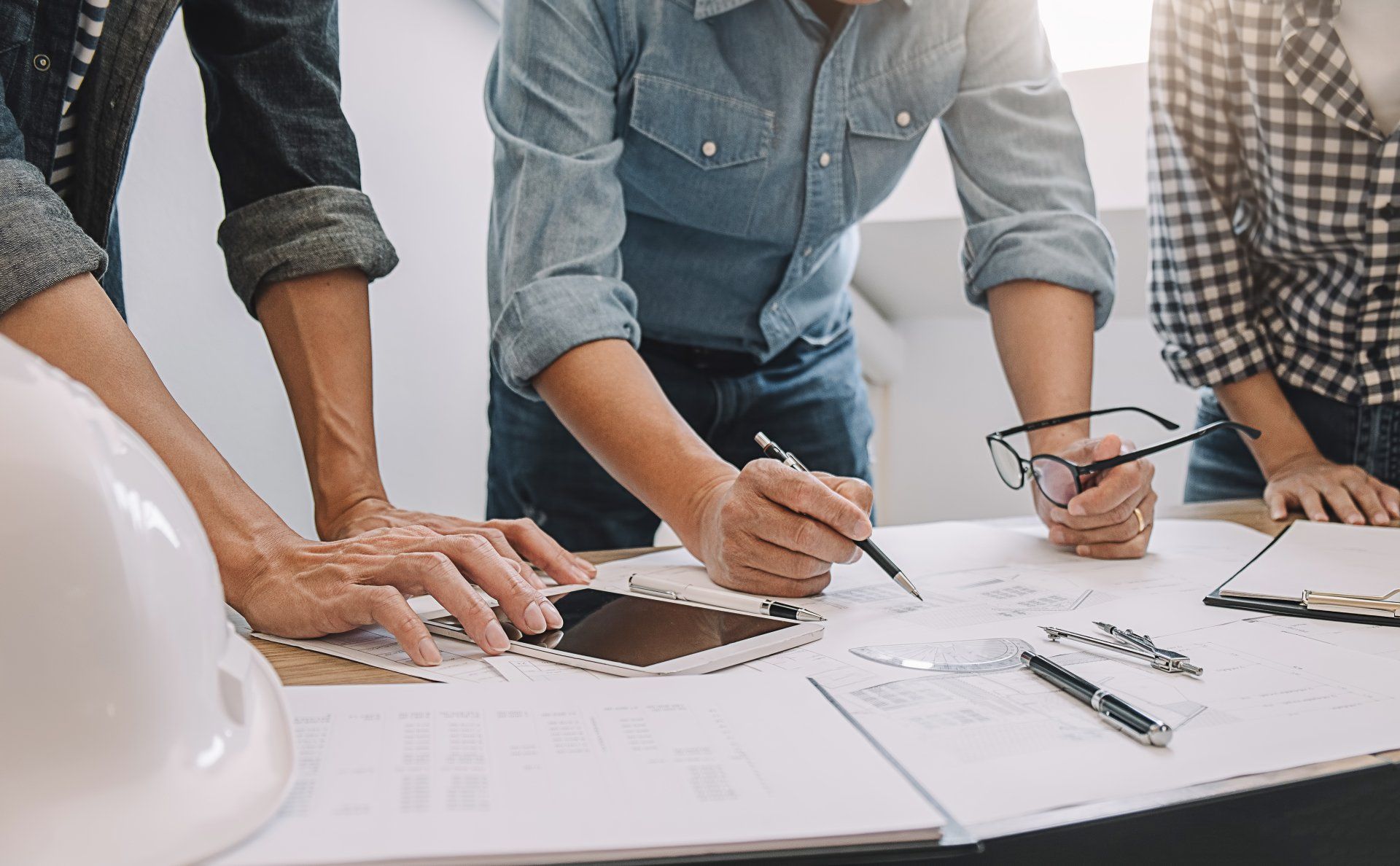 Un groupe de personnes se tient autour d'une table et regarde un plan.