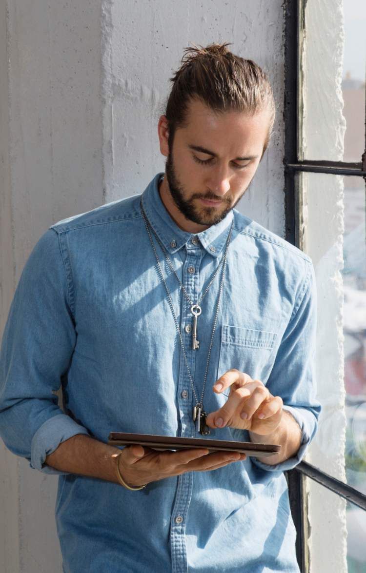 A man in a denim shirt is using a tablet computer.