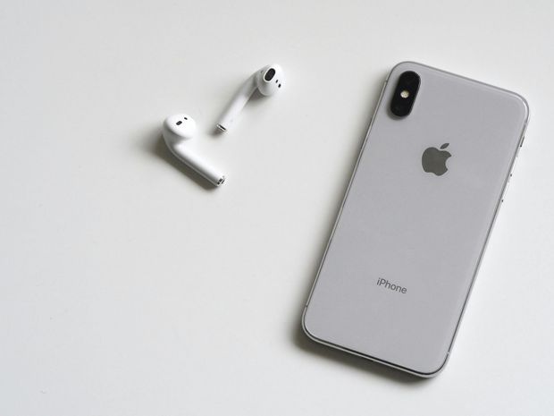 An apple iphone sitting next to a pair of airpods