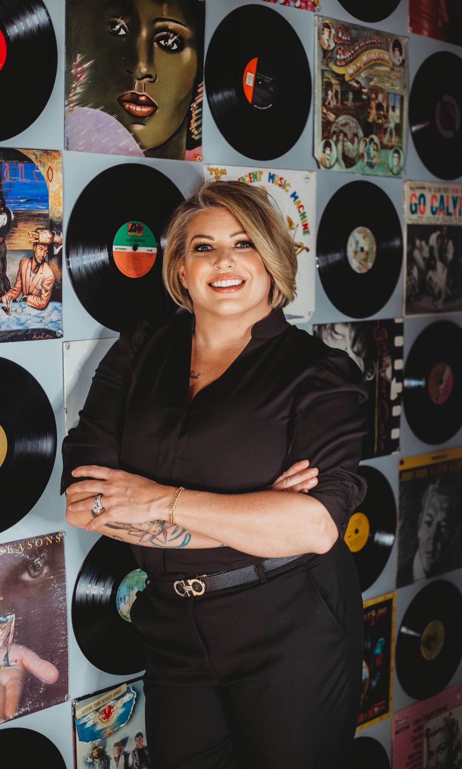 Two women are posing for a picture in front of a pink tinsel backdrop.