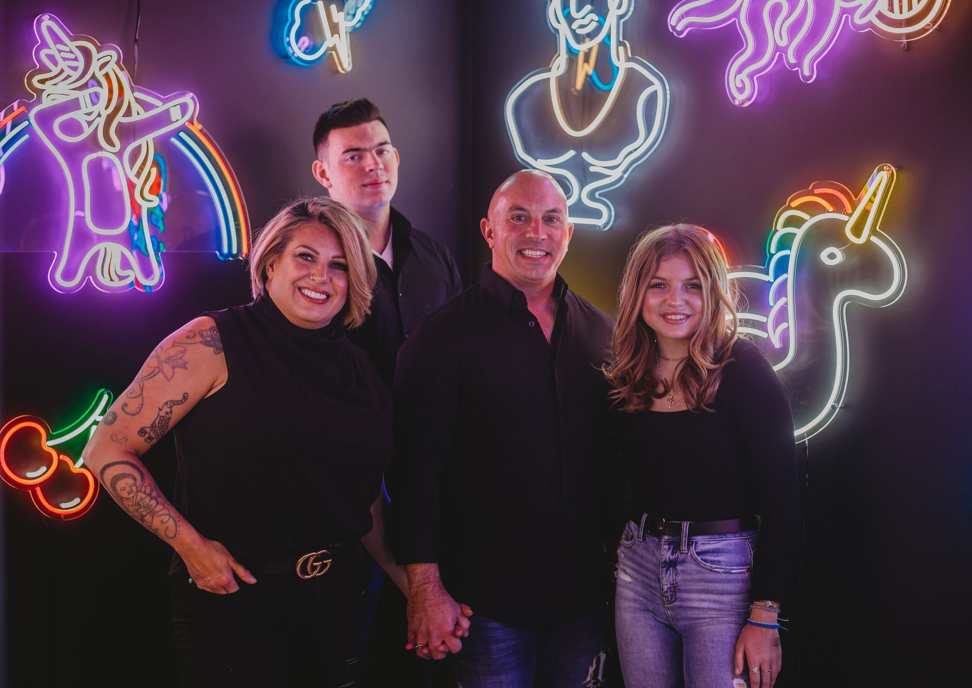 A group of people are posing for a picture in front of a neon sign.