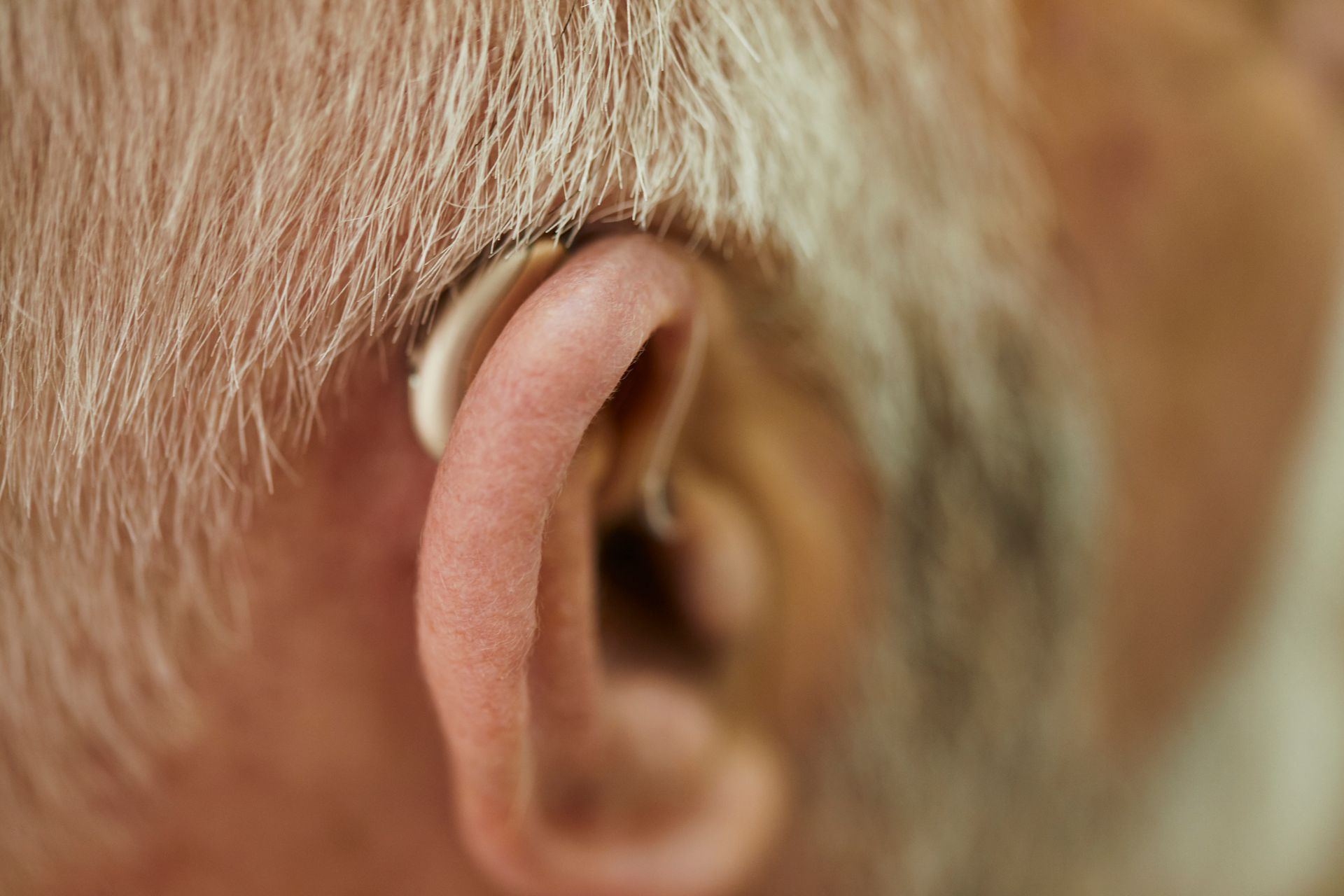 A close up of an older man 's ear with a hearing aid.