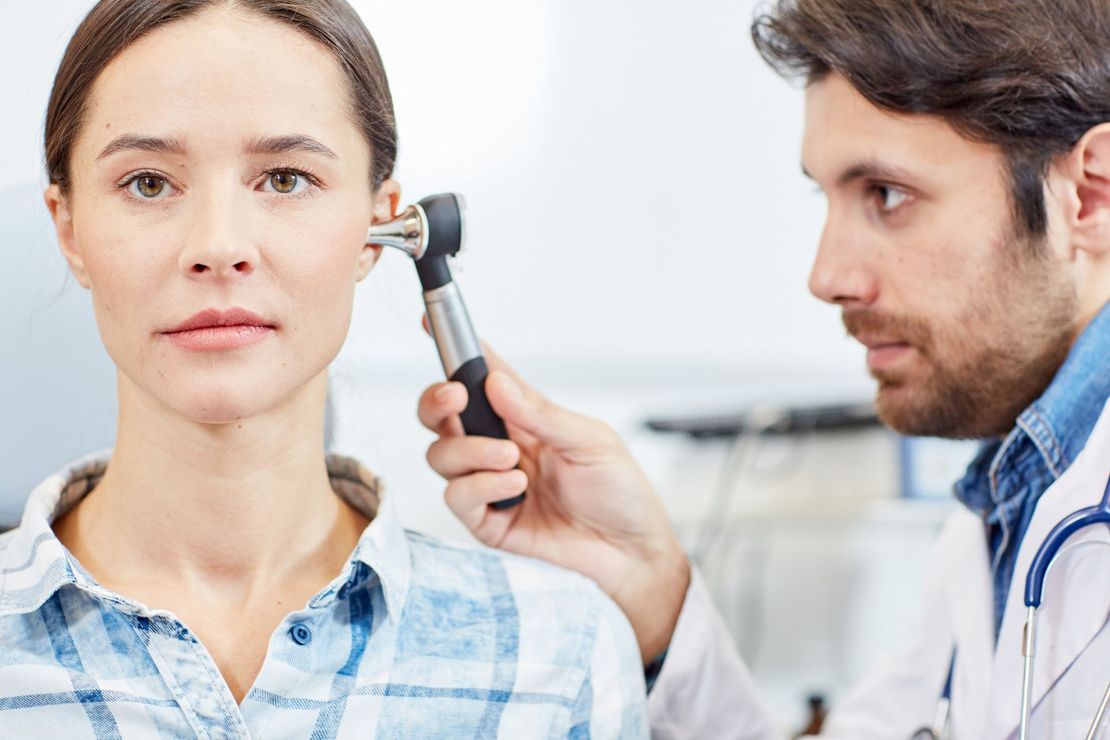 A doctor is examining a woman 's ear with an otoscope.