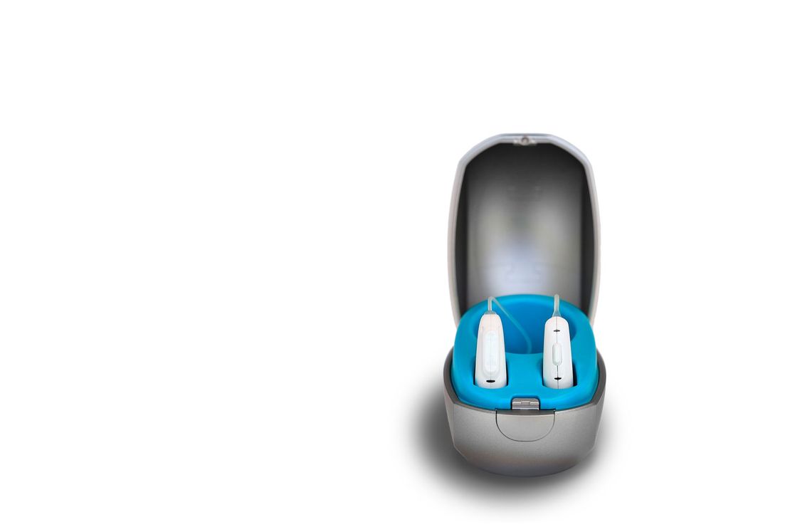 A pair of hearing aids in a case on a white background.