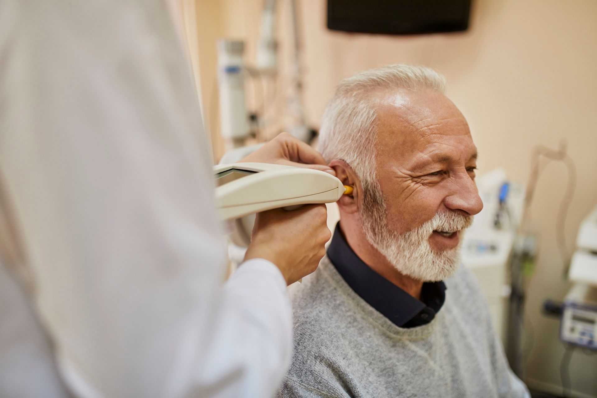 An older man is getting his ears examined by a doctor.