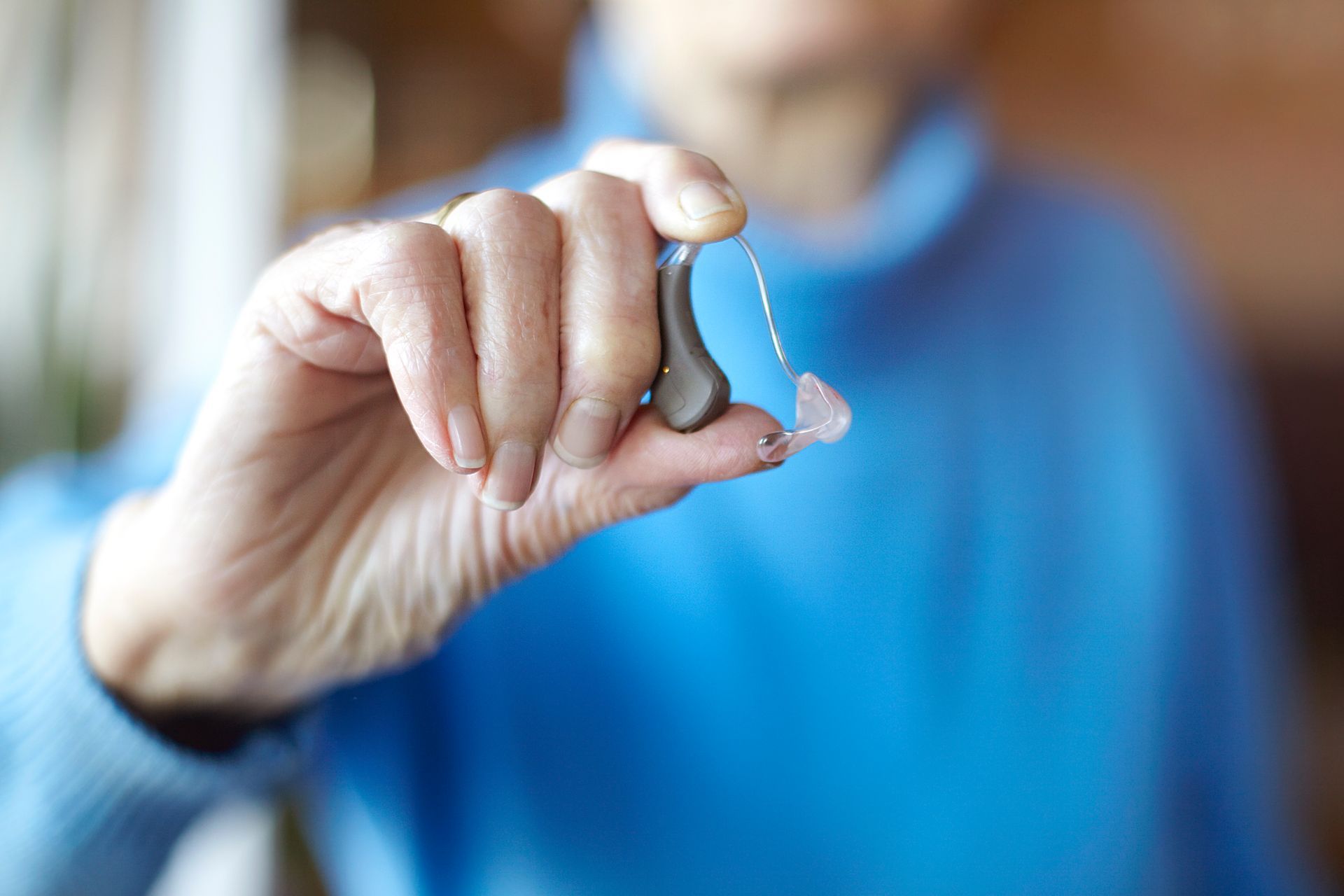 A person is holding a hearing aid in their hand.