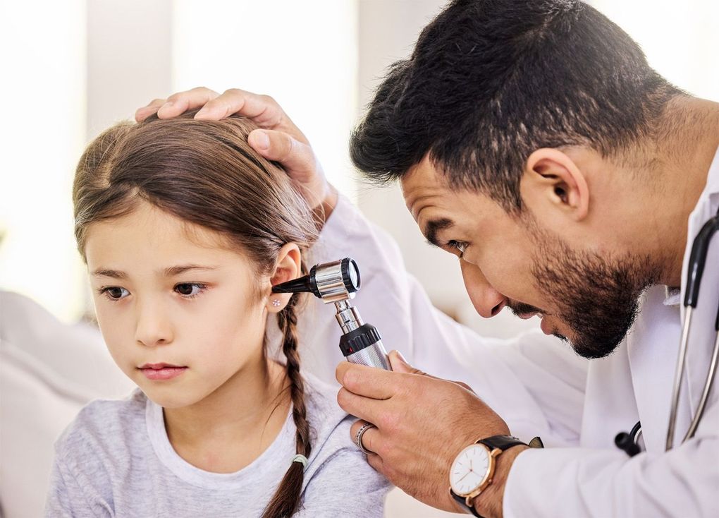 A woman is getting her ears examined by an otolaryngologist.