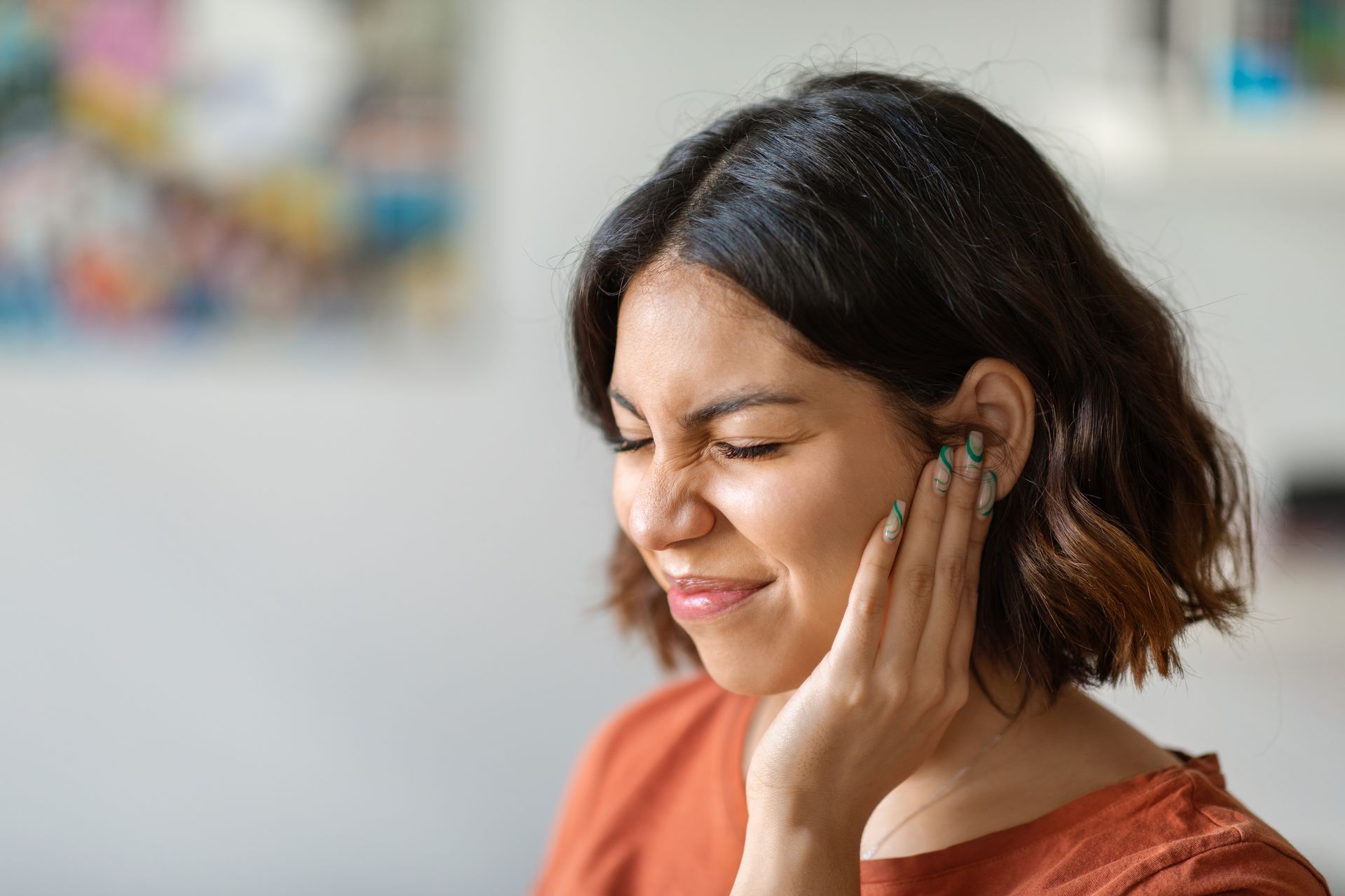 A woman is holding her ear because she has an ear pain.