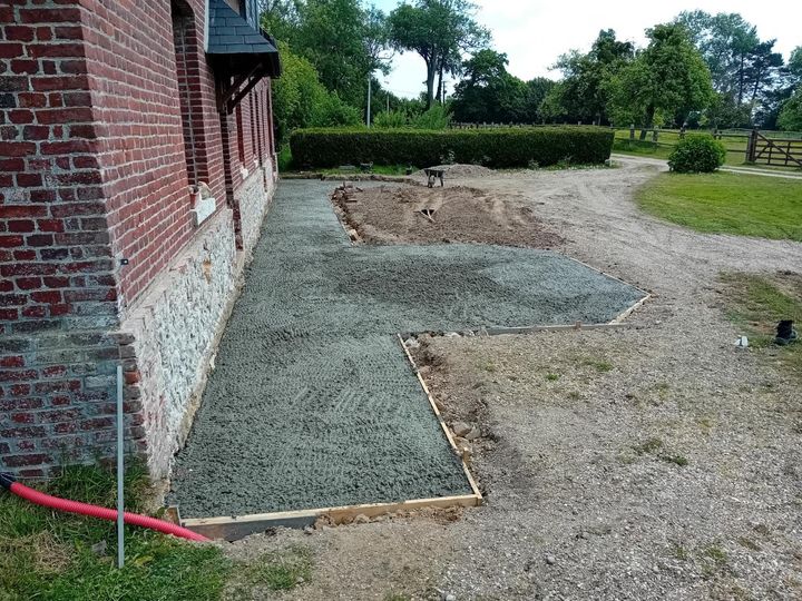 Maison en briques avec des dalles de béton frais le long d'un chemin de gravier et d'une haie de jardin.