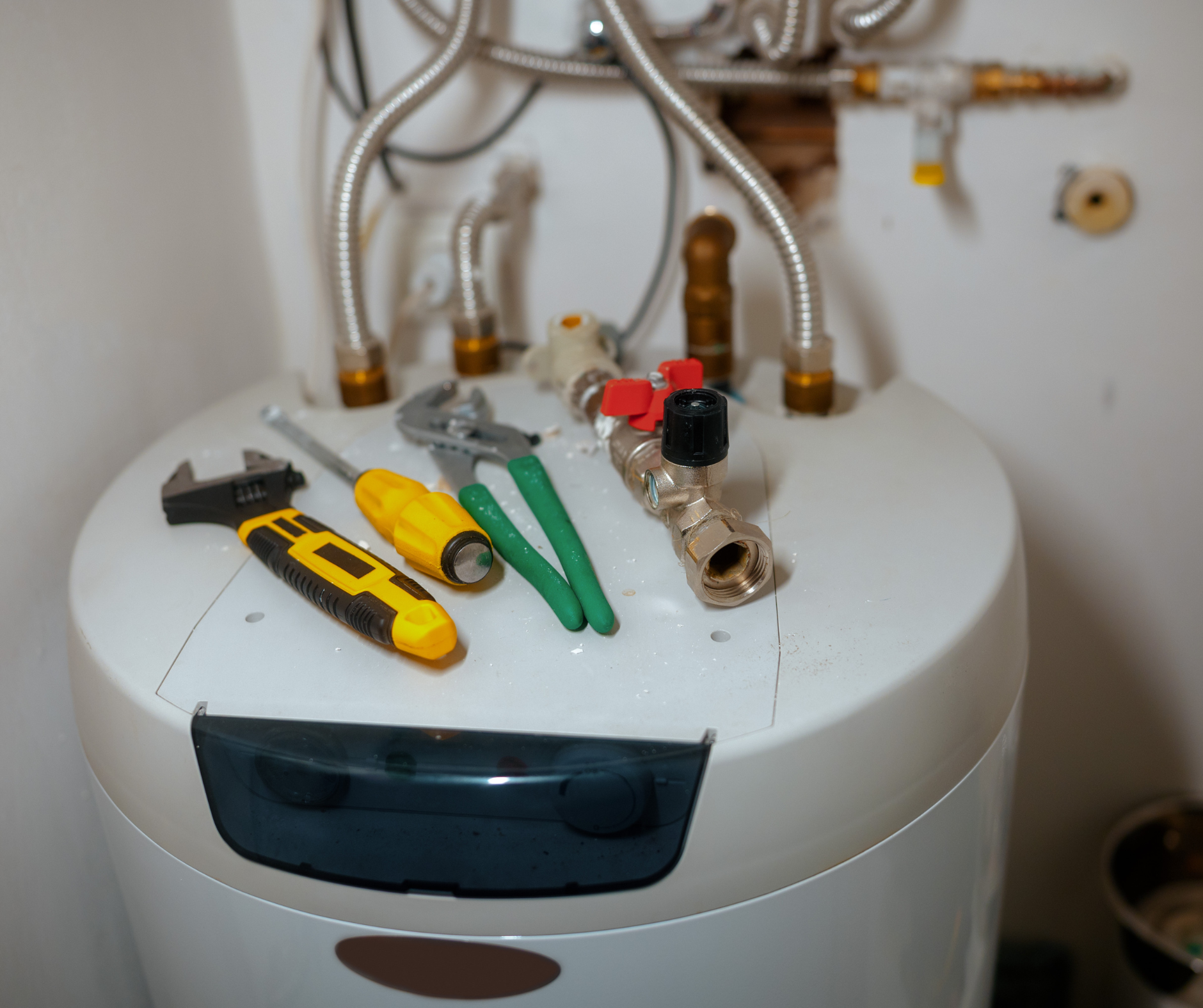 Tools on top of a water heater with pipes.