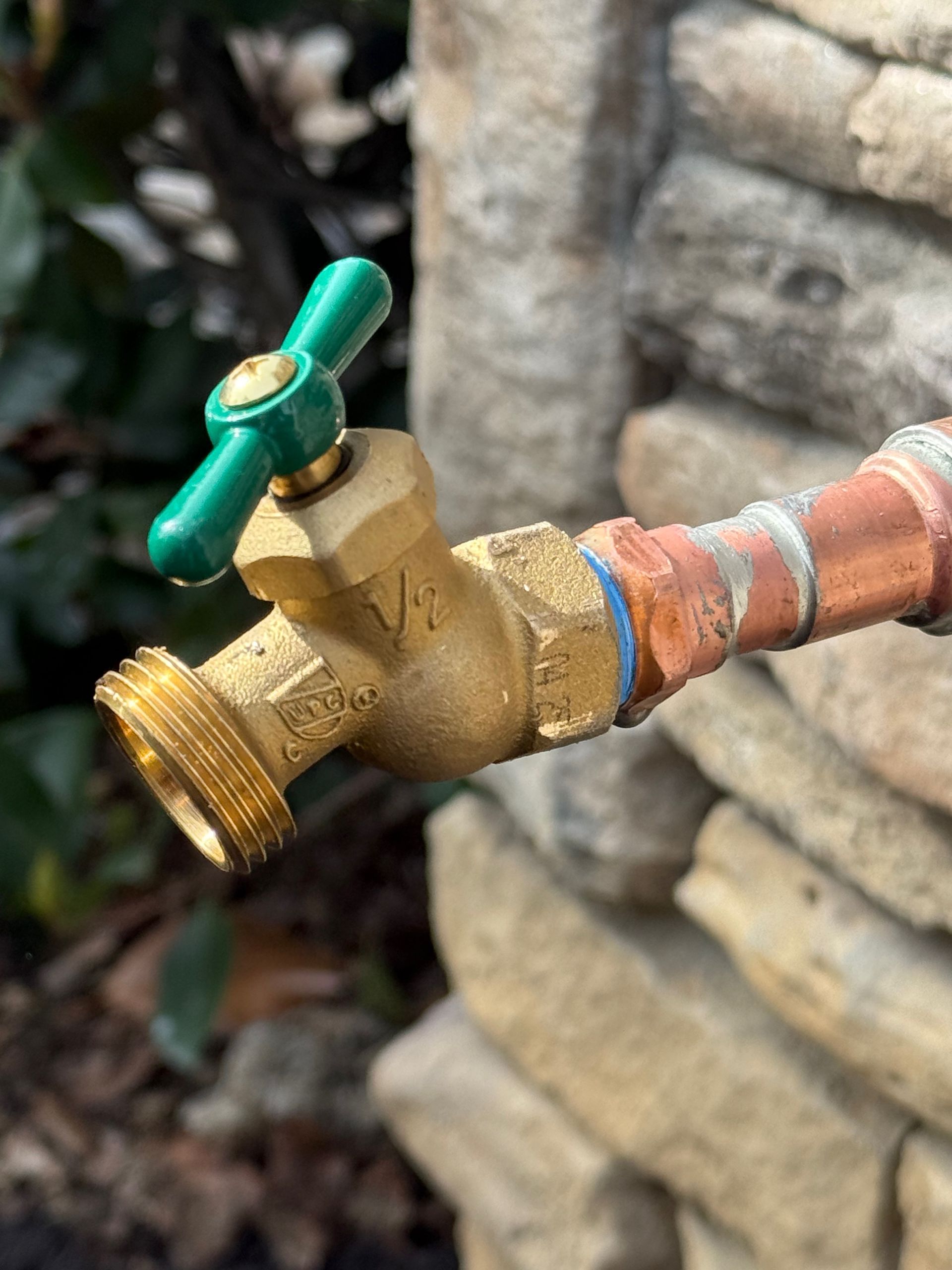 Outdoor water faucet mounted on a white wall.