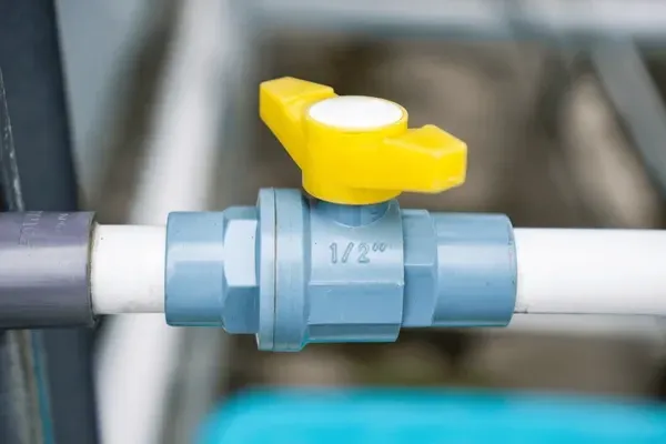 Yellow-handled valve on white and gray pipes, with blue valve body.
