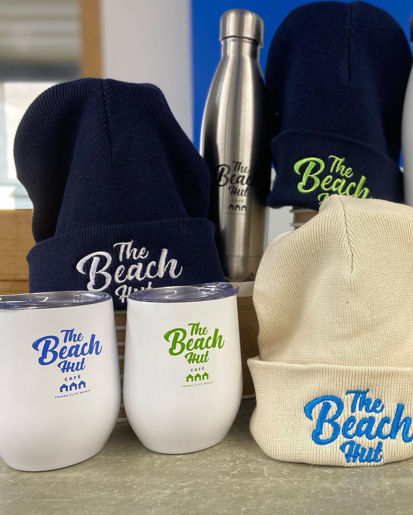 Merchandise display: beanies, insulated cups, and water bottle with