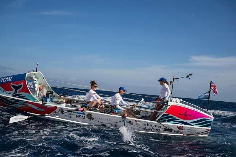 Three people rowing a boat on the ocean. The Worlds Toughest Row