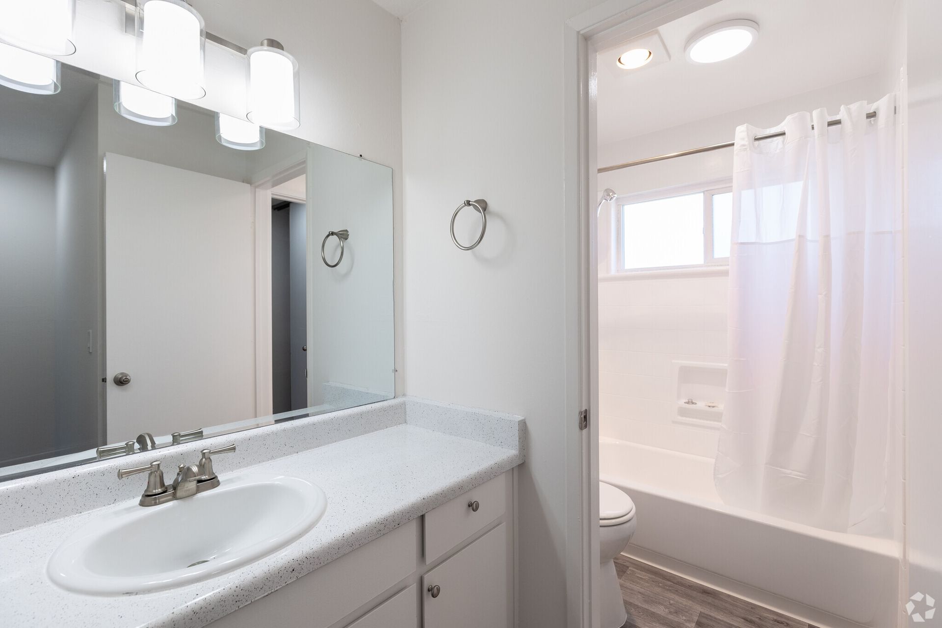 A bathroom with a sink , toilet , shower and mirror.