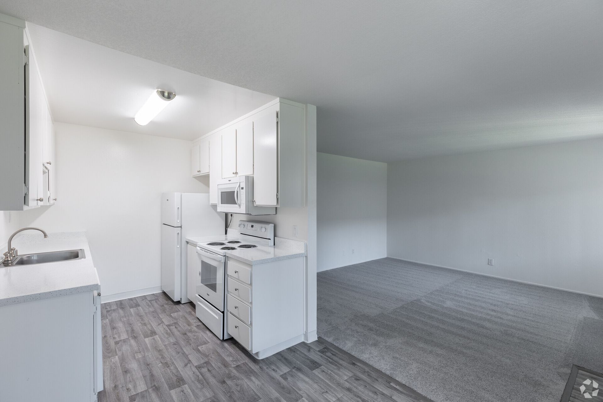 A kitchen with a refrigerator , stove , microwave and sink.