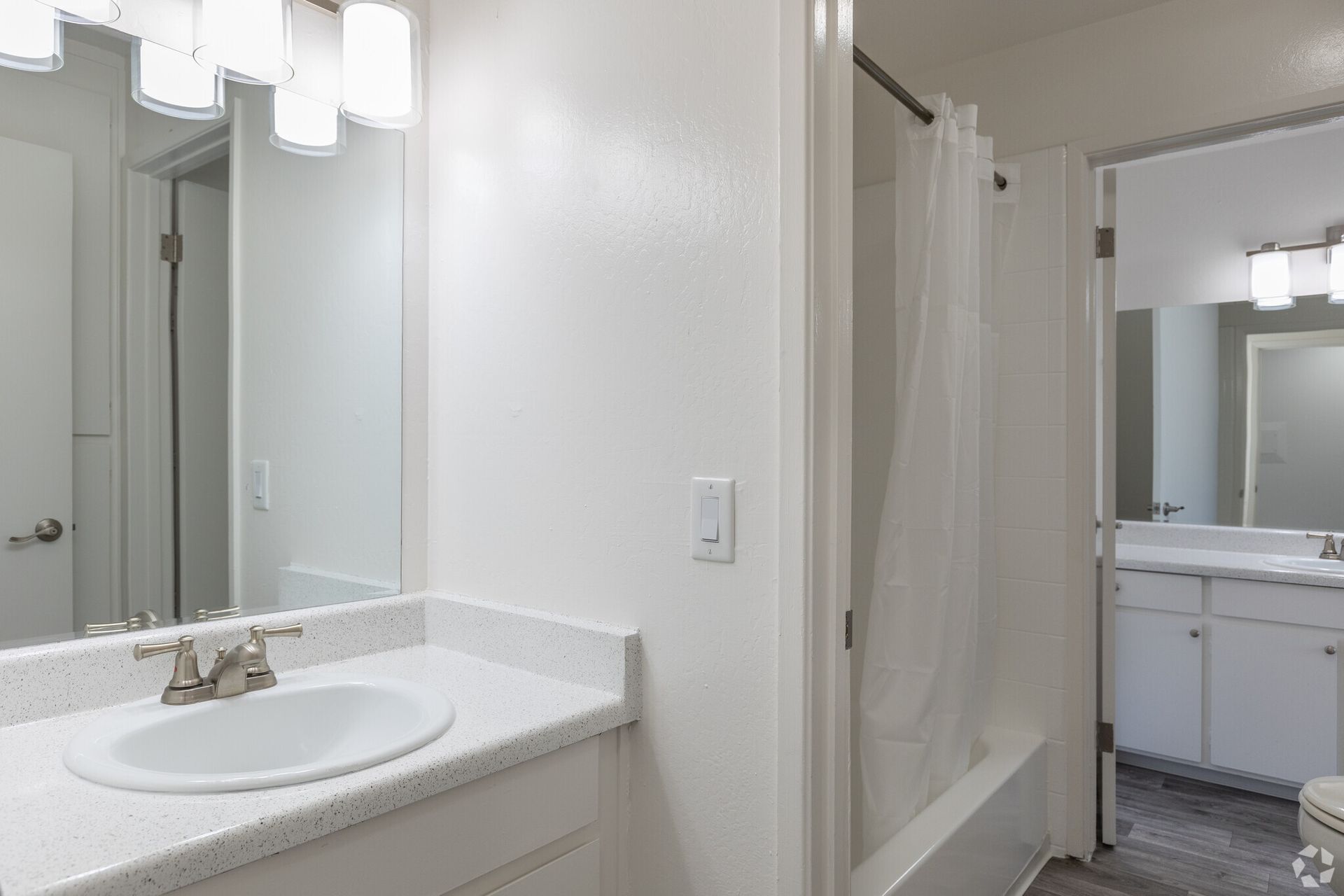 A bathroom with a sink , toilet , shower and mirror.