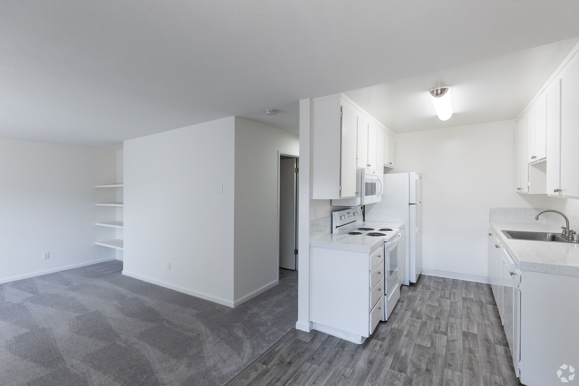 A kitchen with white cabinets , a refrigerator , a microwave , and a sink.